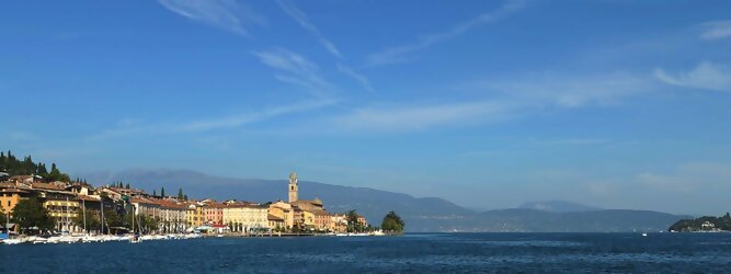 Trip Single beliebte Urlaubsziele am Gardasee -  Mit einer Fläche von 370 km² ist der Gardasee der größte See Italiens. Es liegt am Fuße der Alpen und erstreckt sich über drei Staaten: Lombardei, Venetien und Trentino. Die maximale Tiefe des Sees beträgt 346 m, er hat eine längliche Form und sein nördliches Ende ist sehr schmal. Dort ist der See von den Bergen der Gruppo di Baldo umgeben. Du trittst aus deinem gemütlichen Hotelzimmer und es begrüßt dich die warme italienische Sonne. Du blickst auf den atemberaubenden Gardasee, der in zahlreichen Blautönen schimmert - von tiefem Dunkelblau bis zu funkelndem Türkis. Majestätische Berge umgeben dich, während die Brise sanft deine Haut streichelt und der Duft von blühenden Zitronenbäumen deine Nase kitzelt. Du schlenderst die malerischen, engen Gassen entlang, vorbei an farbenfrohen, blumengeschmückten Häusern. Vereinzelt unterbricht das fröhliche Lachen der Einheimischen die friedvolle Stille. Du fühlst dich wie in einem Traum, der nicht enden will. Jeder Schritt führt dich zu neuen Entdeckungen und Abenteuern. Du probierst die köstliche italienische Küche mit ihren frischen Zutaten und verführerischen Aromen. Die Sonne geht langsam unter und taucht den Himmel in ein leuchtendes Orange-rot - ein spektakulärer Anblick.